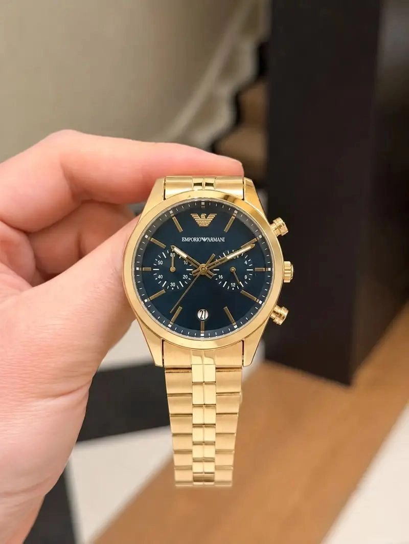 The Emporio Armani Gold Chronograph Watch blends modern sophistication with iconic fashion-inspired styling. Featuring a premium gold-tone stainless steel finish, elegant navy blue sunray dial, multi-function chronograph design, and reliable quartz movement, this timepiece is crafted for men who appreciate refined luxury and everyday elegance. 5